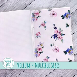 May include: An open notebook with a floral patterned vellum sheet inside. The notebook has a grid pattern on the pages. The vellum sheet has a white background with pink and purple flowers.