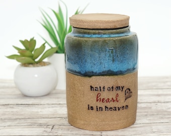 May include: A ceramic jar with a lid, decorated with a blue and brown glaze. The jar has the text "half of my heart is in heaven" written on it.