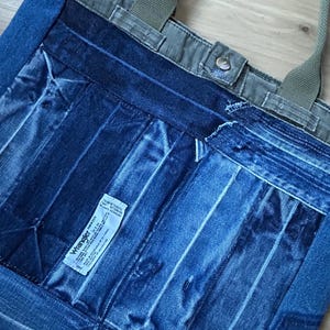Puede incluir: Bolso tote de mezclilla con dise&ntilde;o de patchwork. El bolso presenta una variedad de lavados de mezclilla azul, con una parte superior y correas de lona verde. Una peque&ntilde;a etiqueta blanca con texto negro es visible en la parte delantera.
