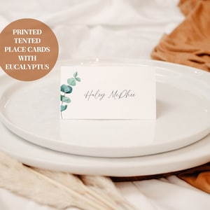 Marque-places sous tente blanche avec détails d'eucalyptus - marque-places pour mariage - avec inscription et étiquette
