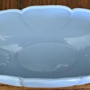 May include: A light blue ceramic serving dish with leaf-shaped handles and a scalloped edge.