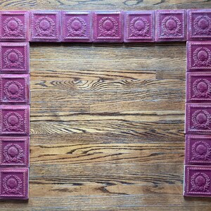 May include: A decorative fireplace surround made of burgundy tiles with a seashell design. The tiles are arranged in a rectangular frame.