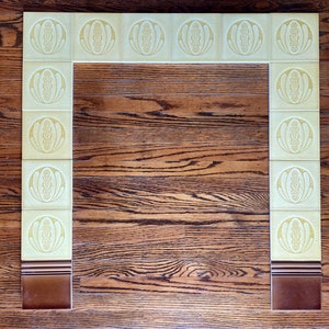 May include: A fireplace surround made of yellow tiles with a brown border. The tiles have a repeating pattern of a stylized flower.