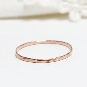 May include: A thin, hammered rose gold band ring.