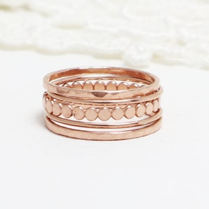 Op de afbeelding: Set van vijf stapelringen van roségoud. De ringen zijn dun en delicaat, met één ring met een rij kleine, ronde kralen.