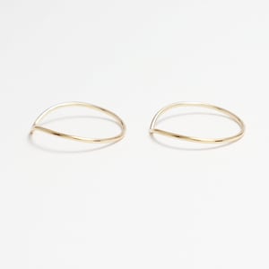 May include: Two thin gold rings with a curved, v-shaped design.