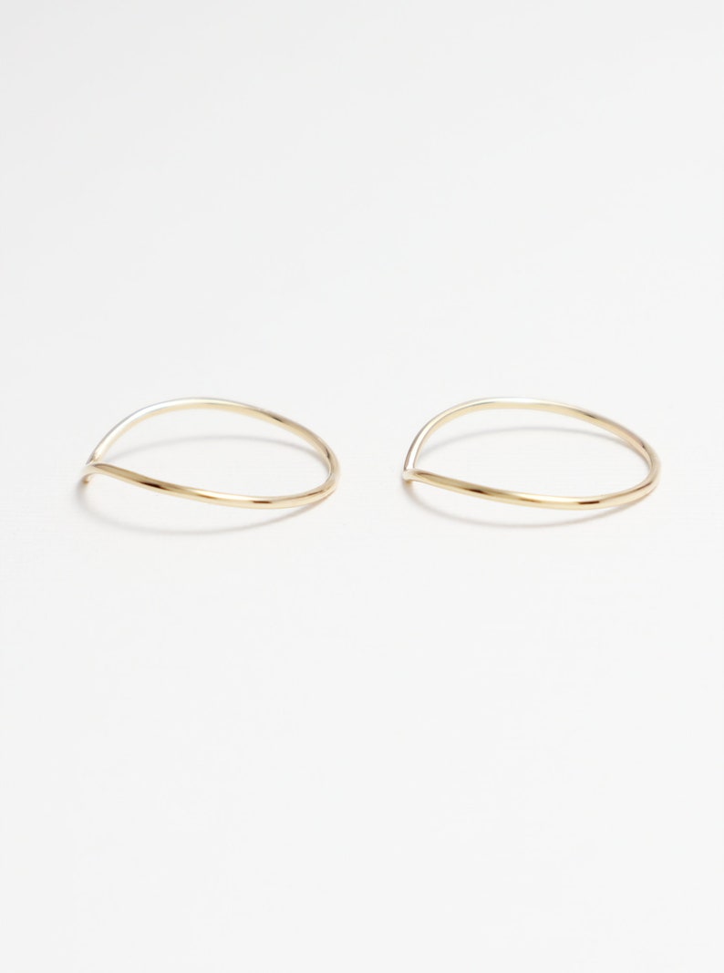 May include: Two thin gold rings with a curved, v-shaped design.