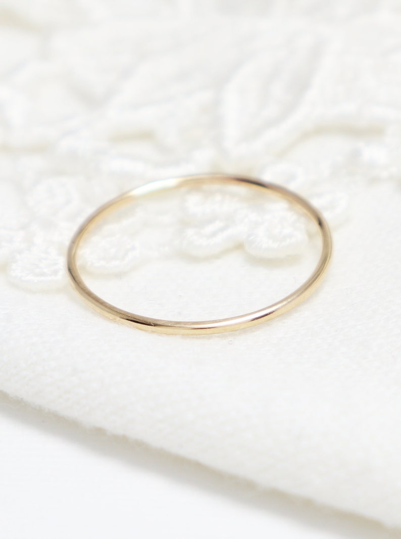 Peut inclure: Une simple bague en or, sur un fond de dentelle blanche.