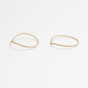 May include: Two thin gold rings with a twisted design. The rings are simple and delicate.