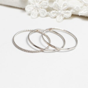 May include: Three silver rings, one with a twisted design, one with a hammered finish, and one with a smooth finish.