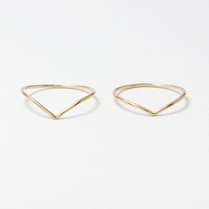 May include: Two gold-coloured, thin, V-shaped rings.