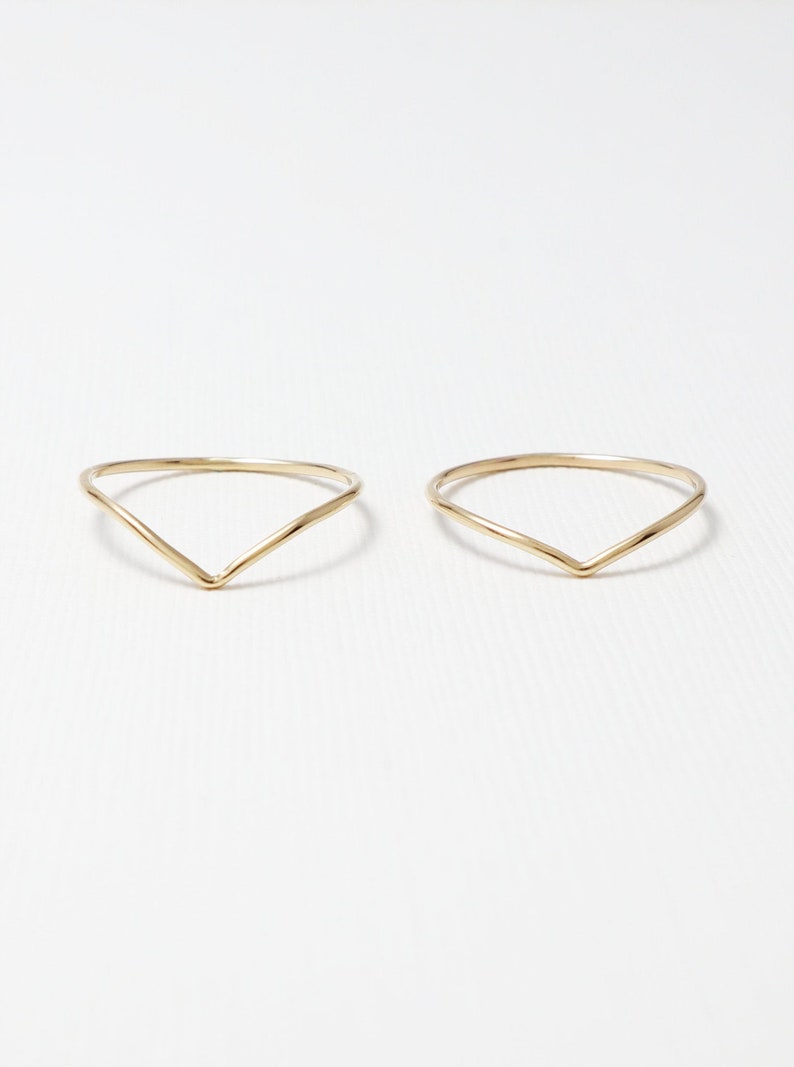 May include: Two gold-coloured, thin, V-shaped rings.