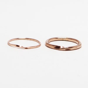 May include: Two gold-colored rings, one with a twisted design and the other with a smooth finish.