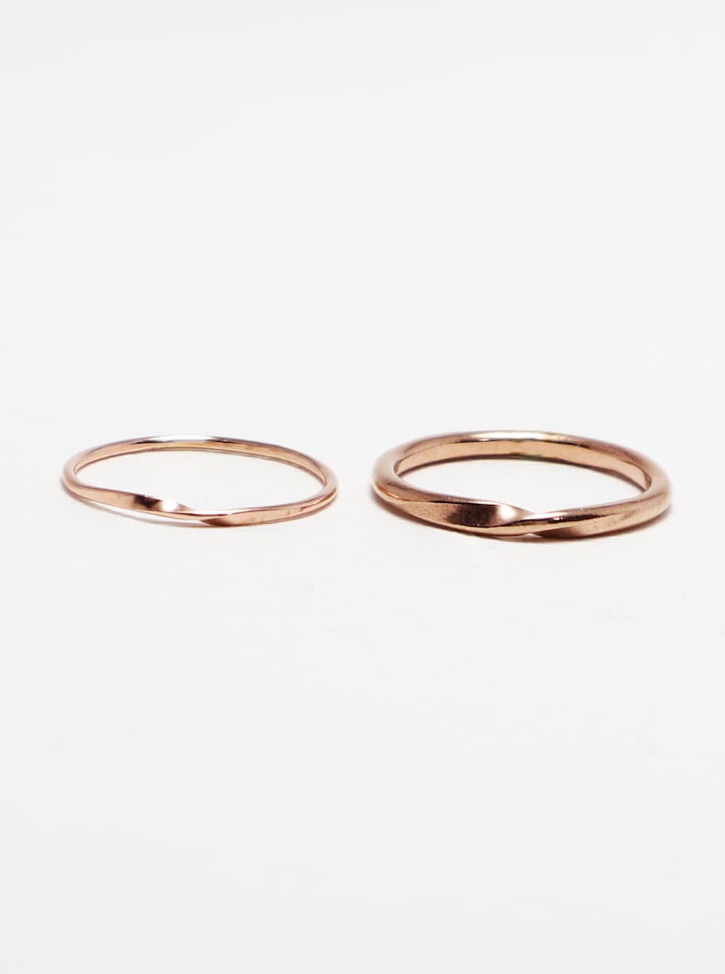 May include: Two gold-colored rings, one with a twisted design and the other with a smooth finish.