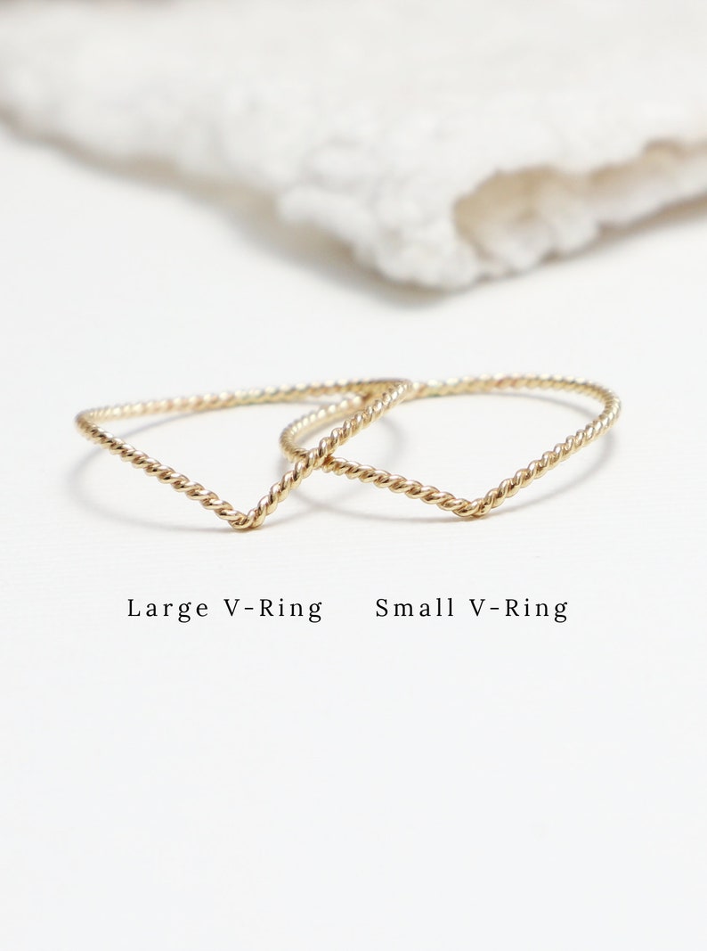 May include: Two gold V-shaped rings, one larger and one smaller, on a white surface. The text "Large V-Ring" and "Small V-Ring" is below the rings.
