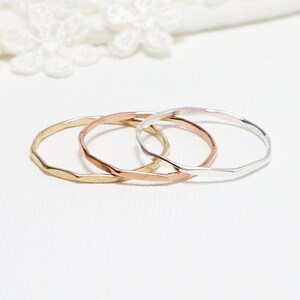 May include: Three thin, hammered metal rings in gold, rose gold, and silver.