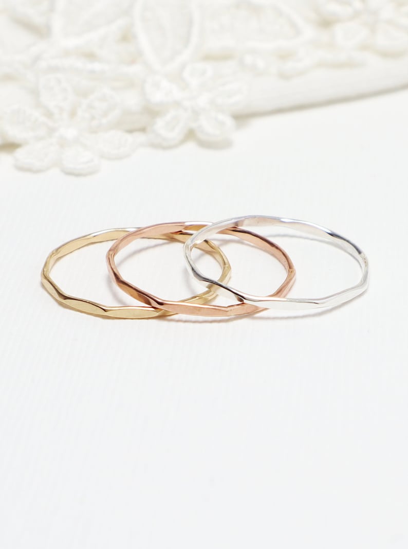 May include: Three thin, hammered metal rings in gold, rose gold, and silver.