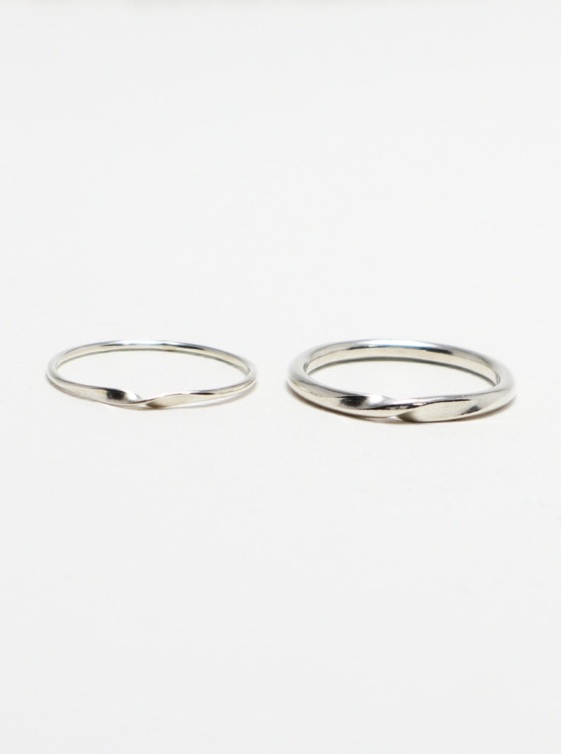 May include: Two silver rings with a twisted design. The rings are simple and elegant.