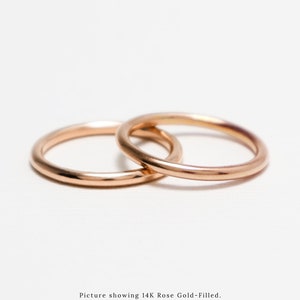May include: Two rose gold rings, interlocked, against a white backdrop. The rings are smooth and shiny, reflecting light. The image text says "Picture showing 14K Rose Gold-Filled."