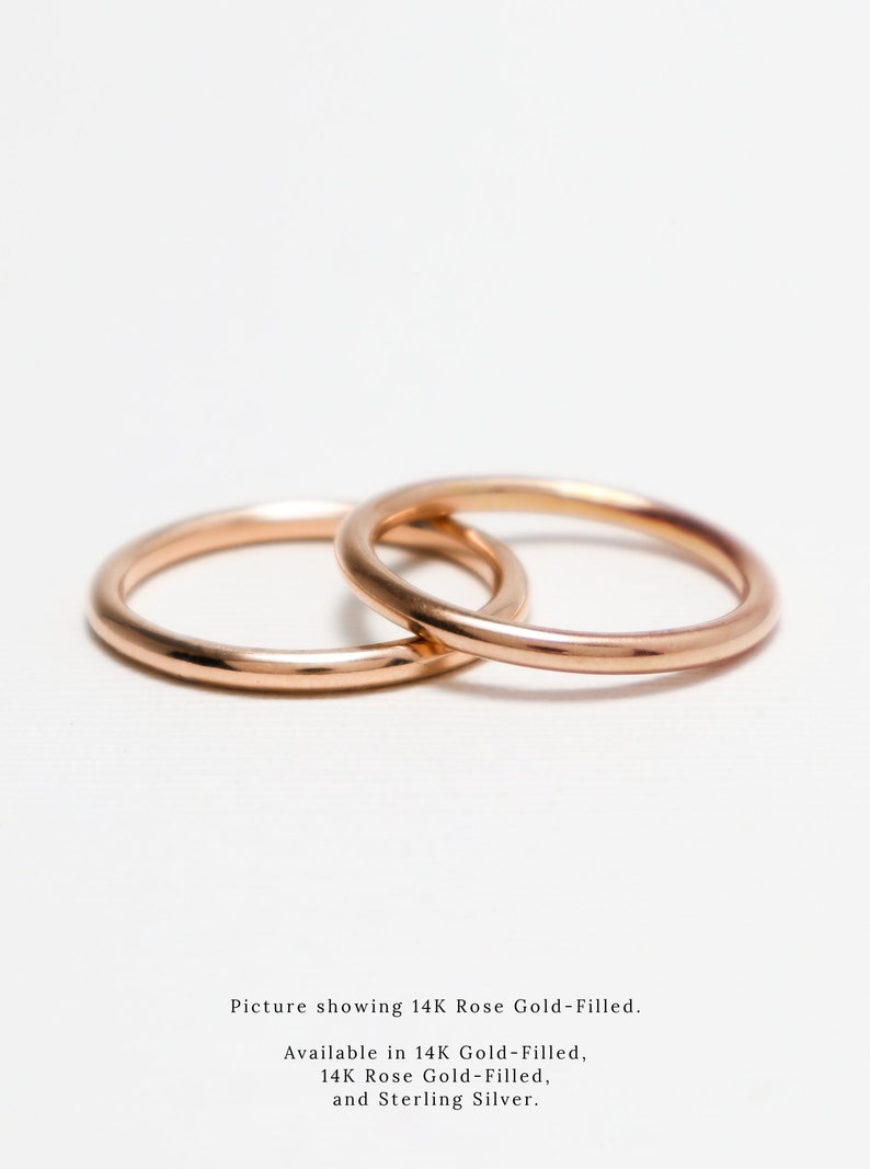 May include: Two rose gold rings, interlocked, against a white backdrop. The rings are smooth and shiny, reflecting light. The image text says "Picture showing 14K Rose Gold-Filled."