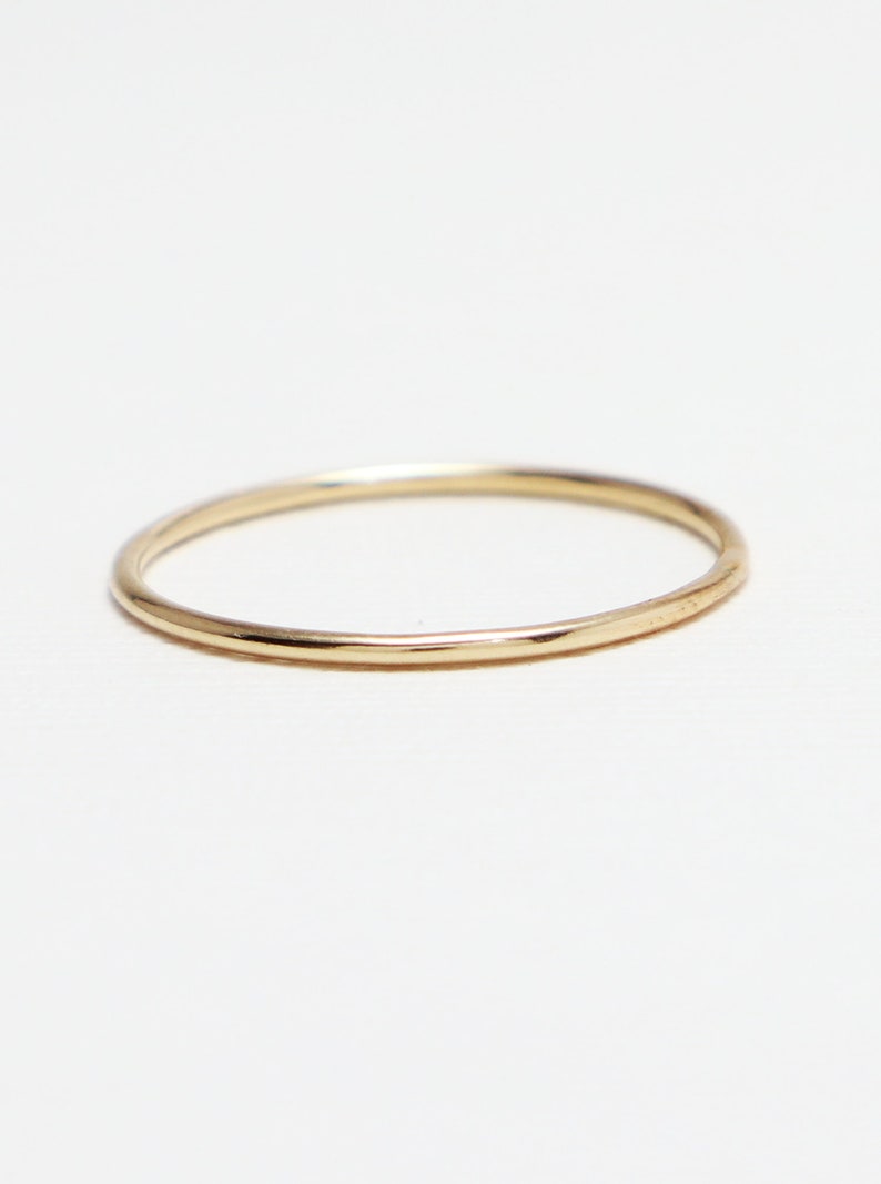Peut inclure: Une bague simple en or. La bague est fine et a une finition lisse et polie.