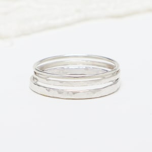 May include: Three silver stacking rings, one with a hammered texture.
