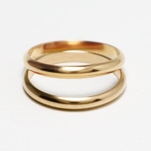 May include: Two gold wedding bands stacked on top of each other.