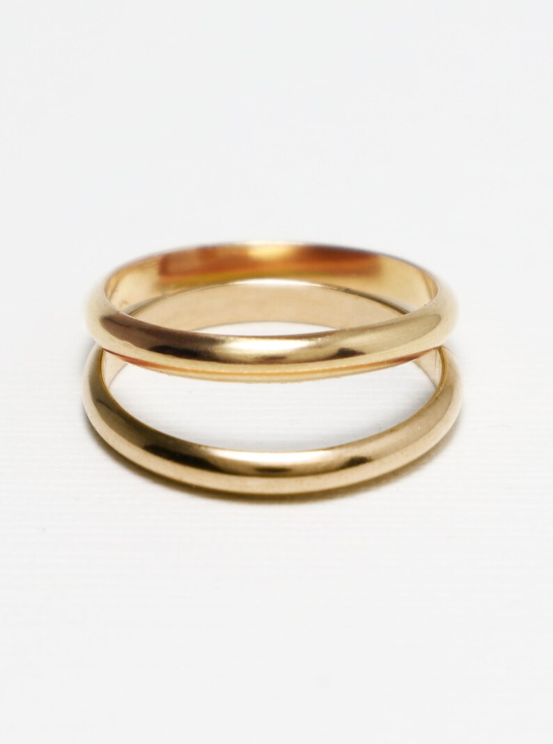 May include: Two gold wedding bands stacked on top of each other.