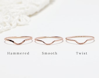 May include: Three gold rings with different textures: hammered, smooth, and twist. Each ring has a curved shape.