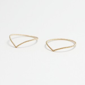 May include: Two gold-coloured, twisted wire rings with a V-shaped opening.
