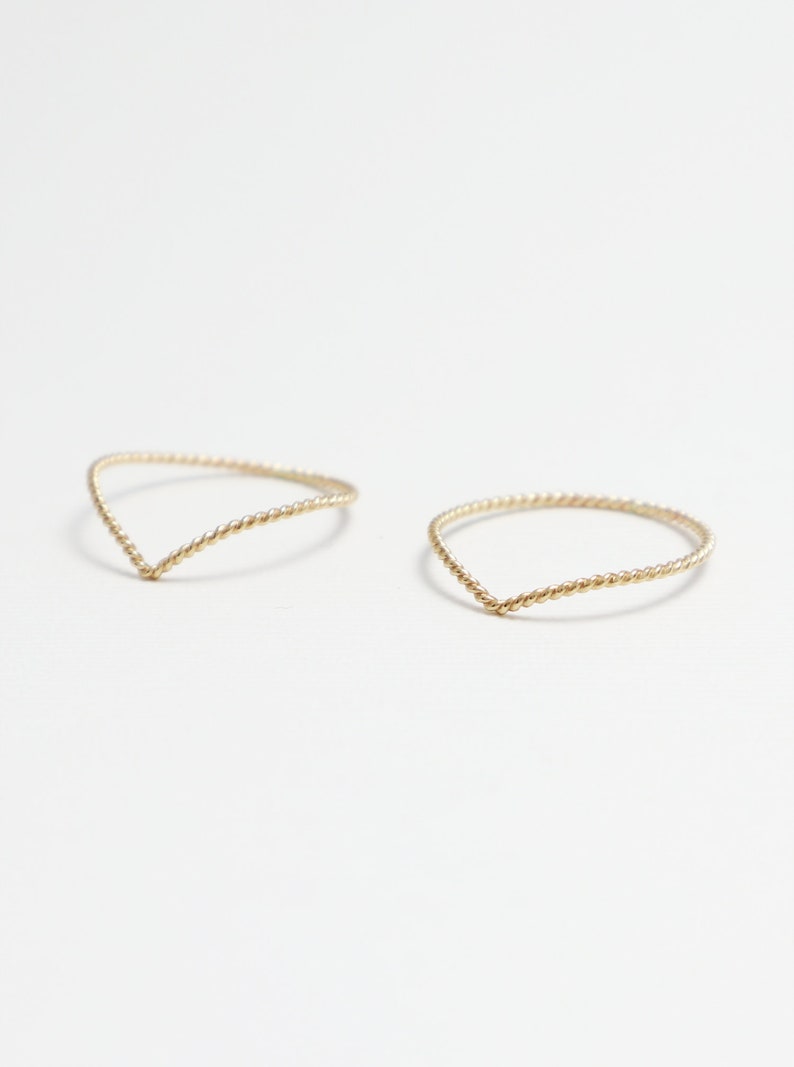 May include: Two gold-coloured, twisted wire rings with a V-shaped opening.