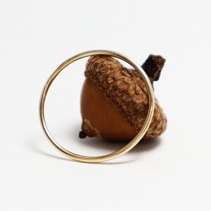 Peut inclure: Une bague en or entoure un gland brun avec un capuchon.