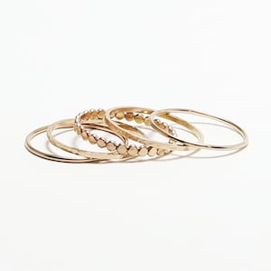 Pu&ograve; includere: Set di quattro anelli impilabili dorati. Un anello ha un design a perline, mentre gli altri tre sono semplici.