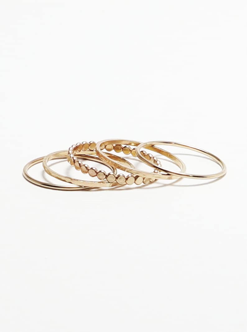Pu&ograve; includere: Set di quattro anelli impilabili dorati. Un anello ha un design a perline, mentre gli altri tre sono semplici.