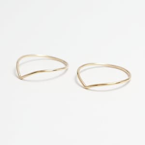 May include: Two gold-coloured, thin, open-ended rings with a V-shaped opening.