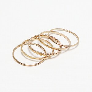 Pu&ograve; includere: Set di cinque anelli in oro, tra cui un anello con design a perline, un anello martellato e tre bande lisce.