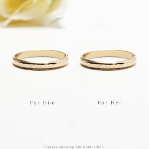 K&ouml;nnte beinhalten: Zwei goldgef&uuml;llte Ringe mit geh&auml;mmerter Textur. Die Ringe werden nebeneinander gezeigt, mit dem Text "F&uuml;r Ihn" und "F&uuml;r Sie" unter jedem Ring. Der Text "Bild zeigt 14 Karat Gold gef&uuml;llt. Erh&auml;ltlich in 14 Karat Gold gef&uuml;llt, 14 Karat Ros&eacute;gold gef&uuml;llt und Sterlingsilber." befindet sich unter den Ringen.