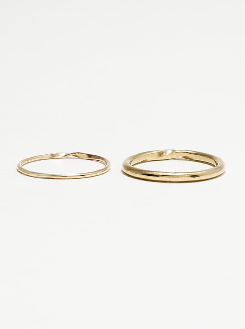 May include: Two gold rings, one with a twisted design and the other with a smooth finish.