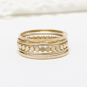 Pu&ograve; includere: Set di cinque anelli impilabili in oro. Gli anelli sono sottili e delicati, con un anello che presenta una fila di piccole perle rotonde.