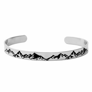 May include: A silver bangle bracelet with a black mountain range design.
