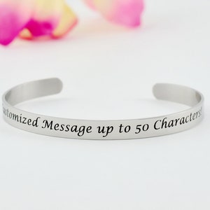 May include: A silver bangle bracelet with the text "Customized Message up to 50 Characters" engraved on the front.