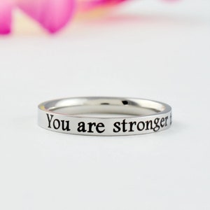 May include: A silver ring with the inscription "You are stronger than you think" engraved on the band.