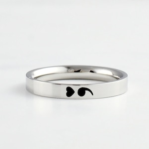 May include: A silver ring with a black heart and semicolon design.