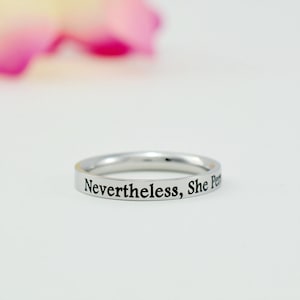 May include: A silver ring with the inscription "Nevertheless, She Persisted" engraved on the band.