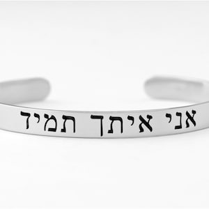 May include: Silver bangle bracelet with the Hebrew words "Ani Achat HaMeir" engraved on it.