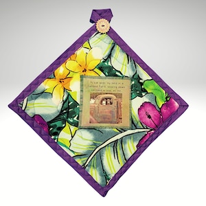 May include: Purple quilted hot pad with a floral print and a vintage car image with the text "It's a goat my lord in a Flatbed Ford, slowing down to take a look at me."