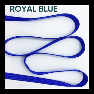 May include: A length of royal blue woven nylon webbing strap arranged in loose, overlapping loops. The material features a consistent, fine-textured grid pattern throughout its surface. The text ROYAL BLUE is printed in dark green at the top.
