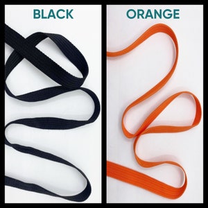May include: A split-screen display showing two lengths of flat woven webbing tape. The left side is labeled BLACK and features a black woven strap. The right side is labeled ORANGE and features a bright orange woven strap with a textured surface.