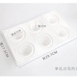 K&ouml;nnte beinhalten: Eine wei&szlig;e Silikonform mit sechs kreisf&ouml;rmigen Vertiefungen, jede mit einem Spiralmuster. Die Form misst 29,7 cm lang, 17,3 cm breit, und die Vertiefungen haben einen Durchmesser von 7 cm und eine H&ouml;he von 3 cm. Der Text zeigt ein Gewicht von ca. 100g an.