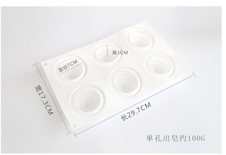 K&ouml;nnte beinhalten: Eine wei&szlig;e Silikonform mit sechs kreisf&ouml;rmigen Vertiefungen, jede mit einem Spiralmuster. Die Form misst 29,7 cm lang, 17,3 cm breit, und die Vertiefungen haben einen Durchmesser von 7 cm und eine H&ouml;he von 3 cm. Der Text zeigt ein Gewicht von ca. 100g an.